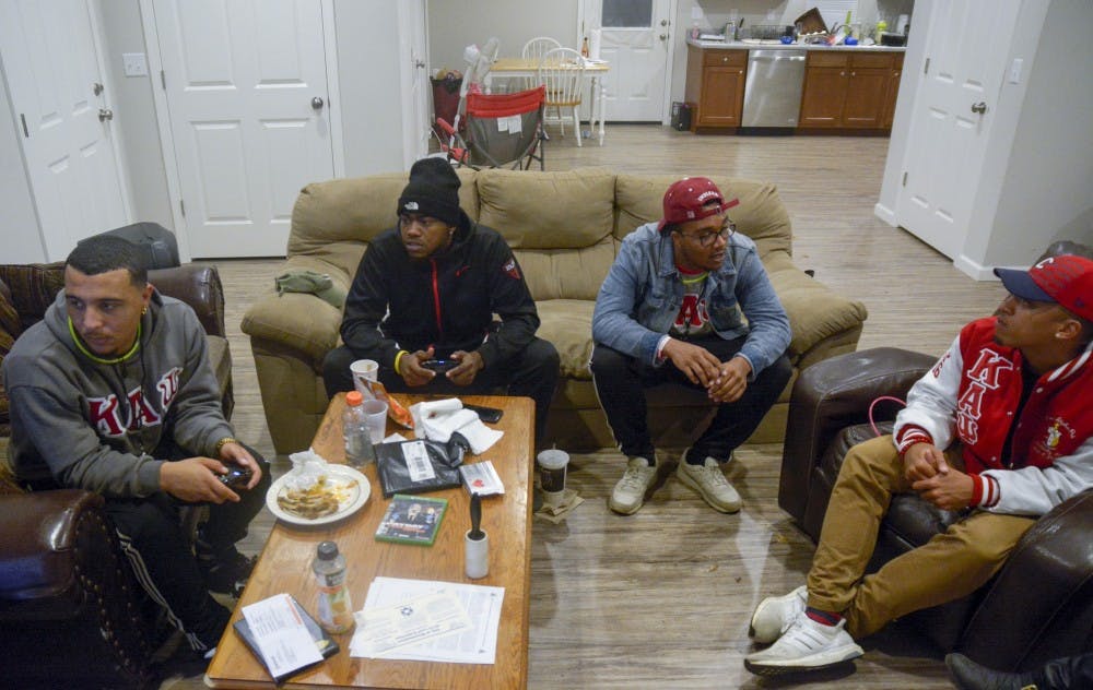 From left, senior Jimmy Hershberger, historian of the fraternity, and junior Damani Roberson, play an intense game of NBA 2K17, while senior Devon Brown, keeper of records, and junior Grant Prather, President of the Alpha Chapter, talk about the history of their fraternity.&nbsp;