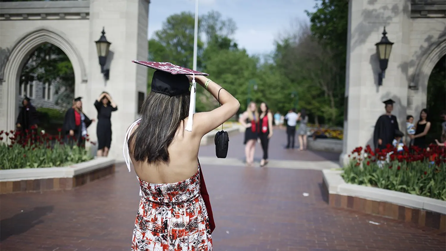Kimia Mirzadeh takes pictures of her friends in front of the Sample Gates on Thursday. Throughout the day, hundreds of graduates flocked to the corner of Indiana and Kirkwood to takes pictures in their caps and gowns.