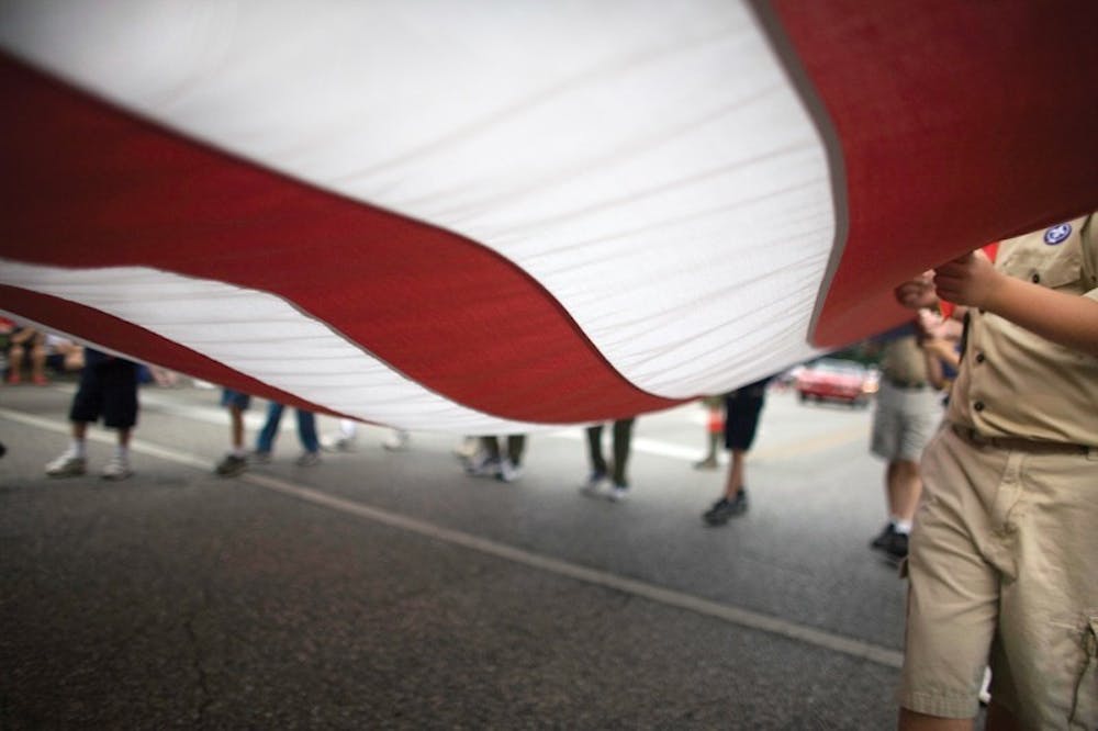 2007年7月4日，独立日游行的参与者手持美国国旗。在独立日反向游行期间，当观众驾车或骑自行车经过时，参赛者将保持静止。
