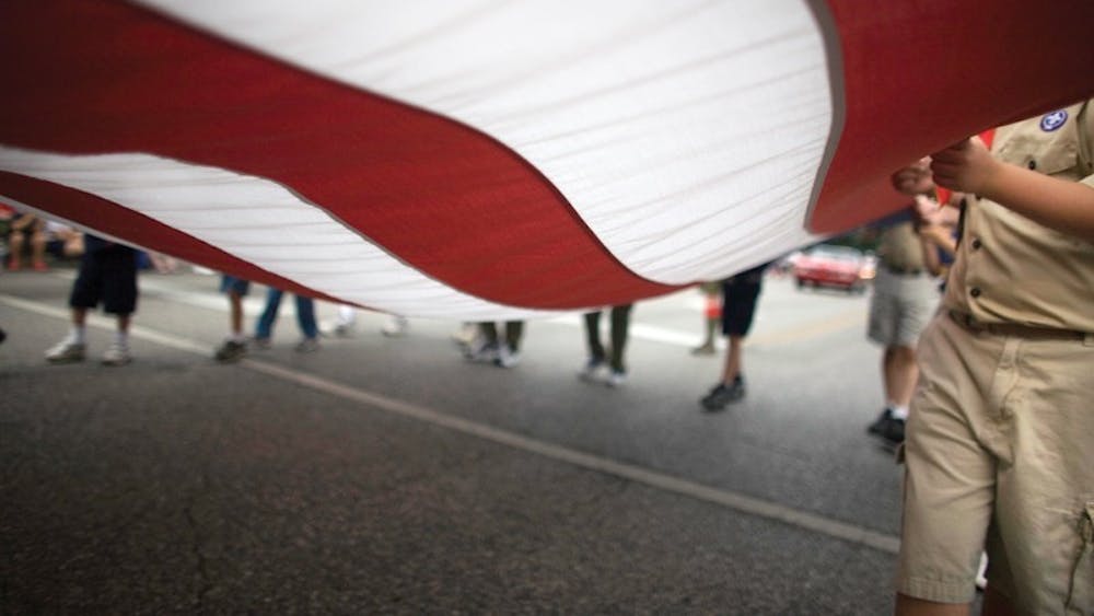 2007年7月4日，参加独立日游行的人举着美国国旗。在独立日逆向游行期间，当观众开车或骑自行车经过时，参赛作品将保持静止。