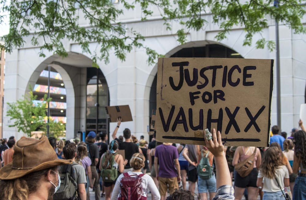 7月6日，一名抗议者在夏洛特·齐特洛司法中心前举起一块牌子。沃克斯·布克是7月4日门罗湖附近种族主义袭击的受害者。