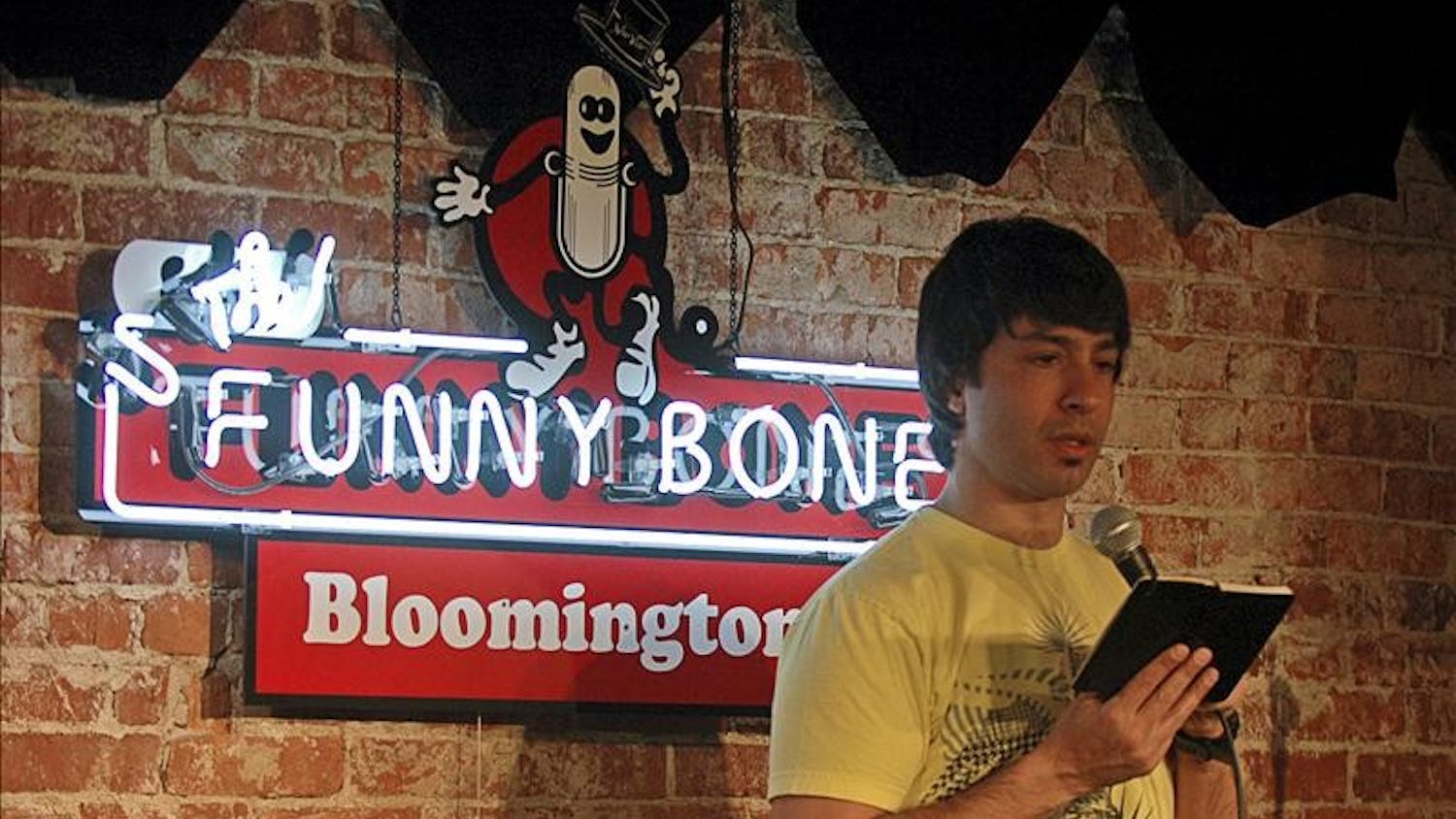 Comedian Arj Barker consults his book of jokes Thursday evening at The Funny Bone. Barker was in town for five performances over the weekend.
