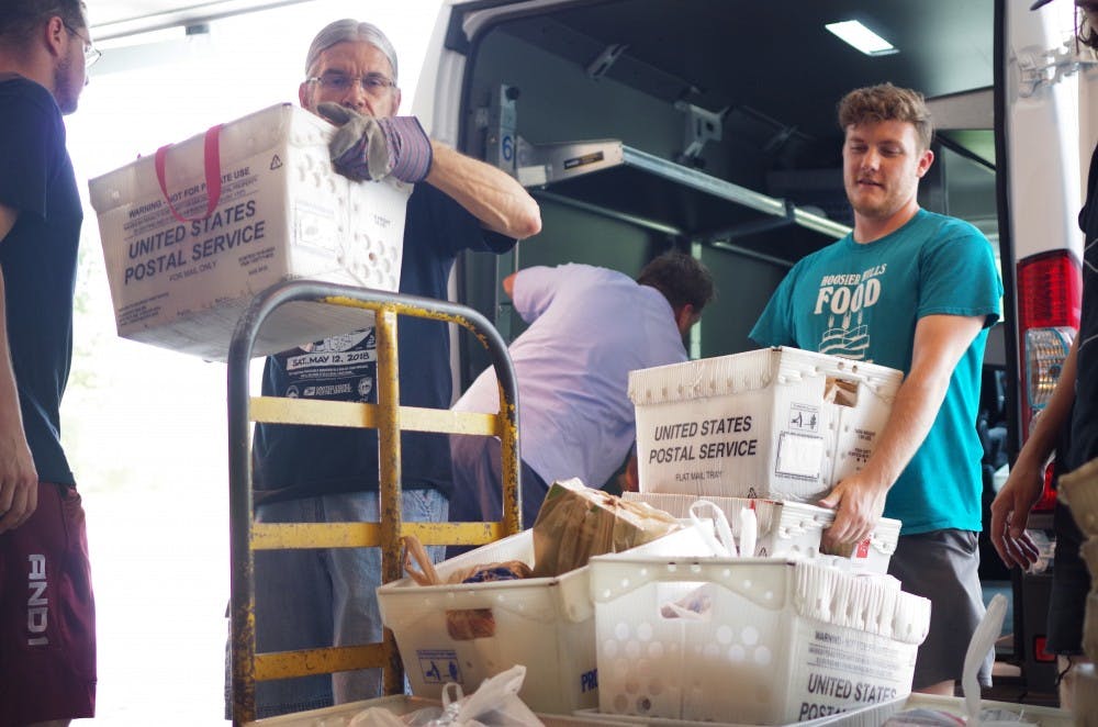 <p>Dan Morelli, left, and Brandon Bartley, right, unload a U.S. Postal Service van during the Stamp Out Hunger food drive May 12.</p>