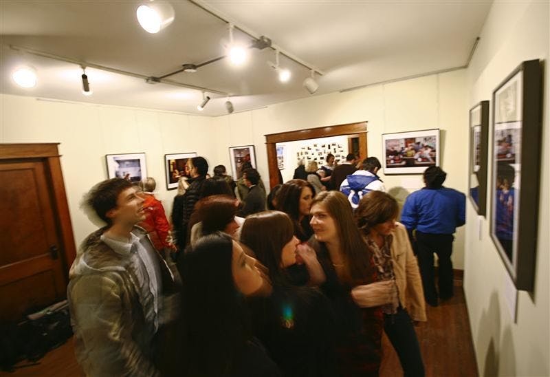 Friends look at art during the "No Man Is Island" BFA Show Friday evening at the Art Hospital on Allen Street. The students worked together on various projects, themed on issues the media ignores.