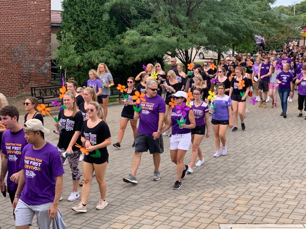 在结束阿尔茨海默病的步行过程中，参与者携带一朵花，代表他们的疾病之旅；2019年9月15日。从步行中筹集的资金直接捐给老年痴呆症协会。