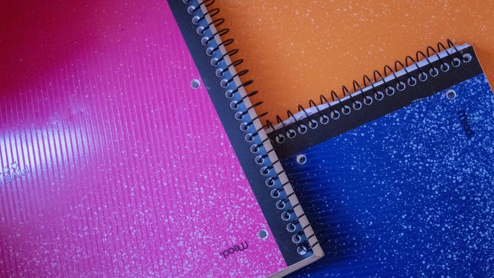 A stack of notebooks sits on a desk. 