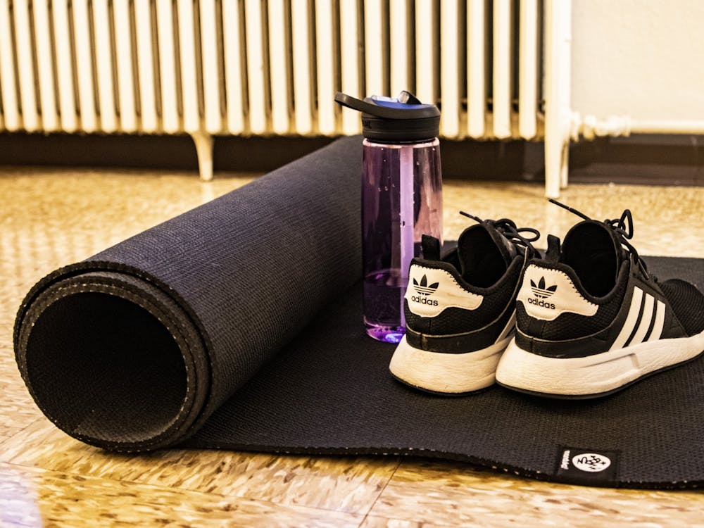 Adidas sneakers and a Camelbak water bottle sit on a yoga mat March 30 at University East apartments. Many IU students use their time while quarantining to practice self-care through activities such as yoga.