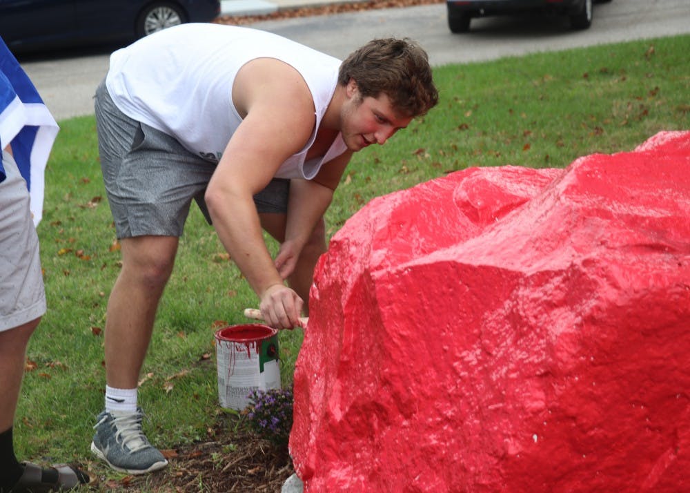 A member of Sigma Nu paints a rock red Wednesday afternoon outside their house on North Jordan Ave. before being called back into the house. The Beta Eta chapter of Sigma Nu was suspended from the IU campus by its national leadership due to alleged hazing and alcohol related violations.