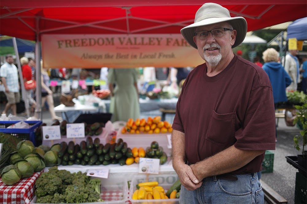 Jim Baughman stands in from of his "Freedom Valley Farms" tent at the Bloomington Community Farmers' Market on Saturday.  Baughman has owned and operated the farm with his brother for five years.    