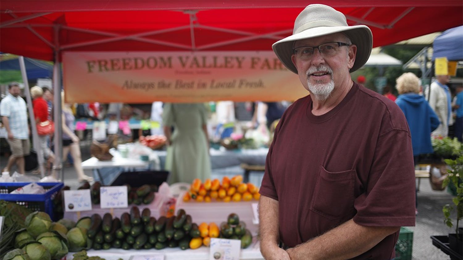 Jim Baughman stands in from of his "Freedom Valley Farms" tent at the Bloomington Community Farmers' Market on Saturday.  Baughman has owned and operated the farm with his brother for five years.    
