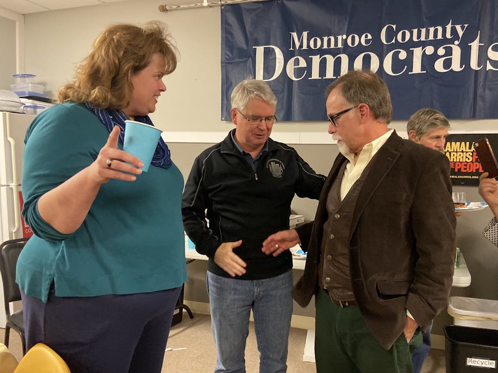 Mayor John Hamilton, center, and Ron Smith shake hands while talking with Sue Sgambelluri on Tuesday night at the election watch party for the Monroe County Democrats. Smith won the election for Bloomington City Council District 3, and Sgambelluri won the District 2 race.