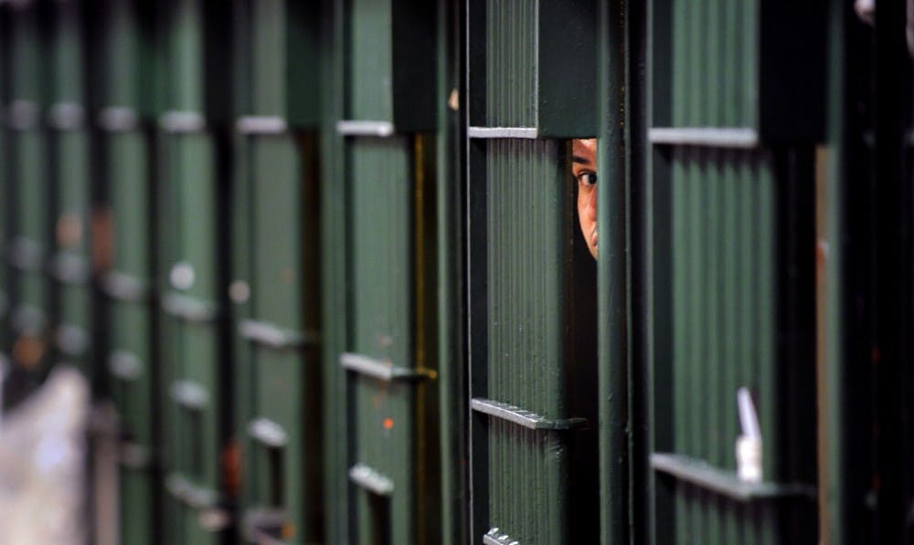 An inmate peeks through the bars at a restrictive housing unit, formerly known as solitary confinement, on June 2, 2016, at the Men&#x27;s Central Jail in Los Angeles.  