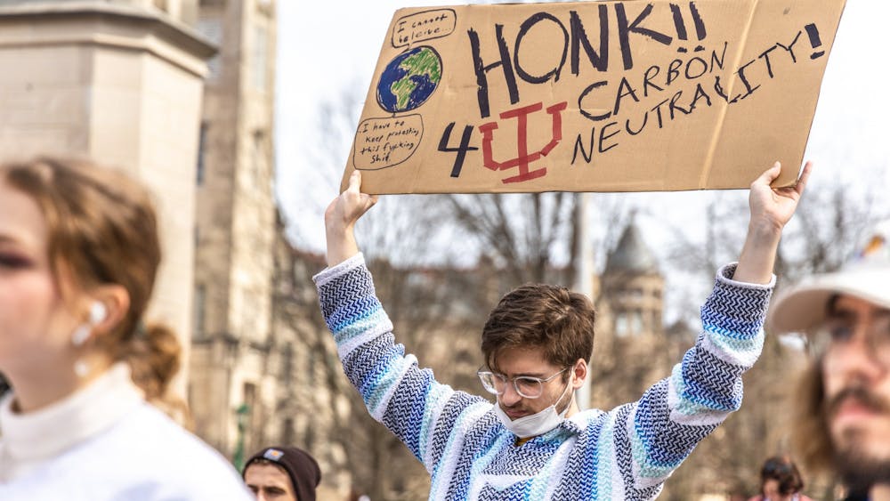 IU junior George Schafer listens to a speaker during Students for a New Green World&#x27;s protest for climate action March 4, 2022, in front of Sample Gates. The student organization wants IU to divest from fossil fuels and be carbon neutral by 2040. 
