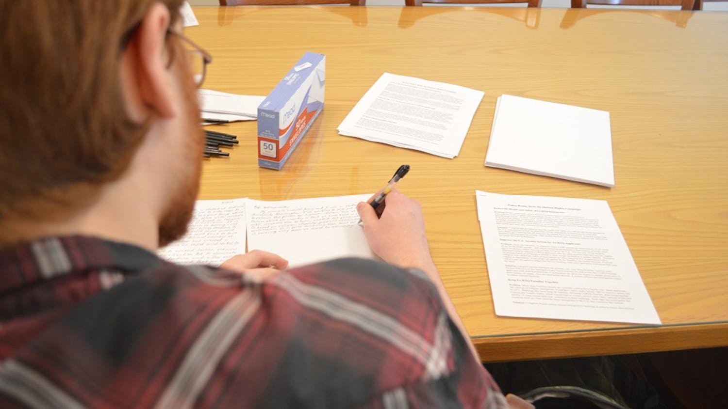 Senior Samuel Young writes letters to legislators to advocate for inclusive reform Tuesday evening at the Canterbury House. He also wrote letters about current immigration policies affecting LGBT people. 