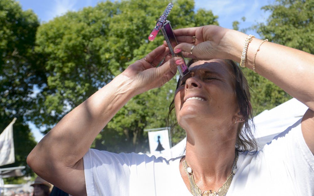 Terri Anderson interacts with glass art, "Frieworks" Kaieidoscopes by Kathleen Hunt, on Sunday morning at Fourth Street Festival of the Arts and Crafts. 