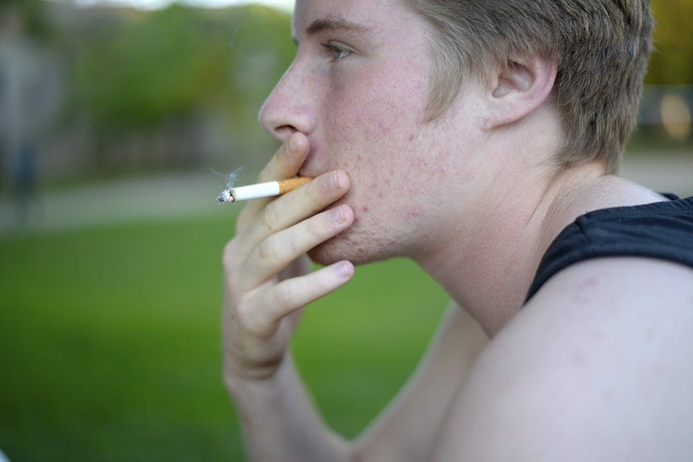 Freshman James Freeborn smokes a cigarette Sunday near the smokers' table outside of Wright Quadrangle.