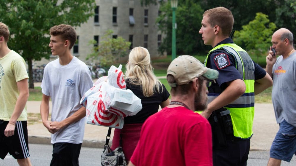 An IU police officer assists people at a crosswalk during move-in week Aug. 15 between Wright and Teter quads.