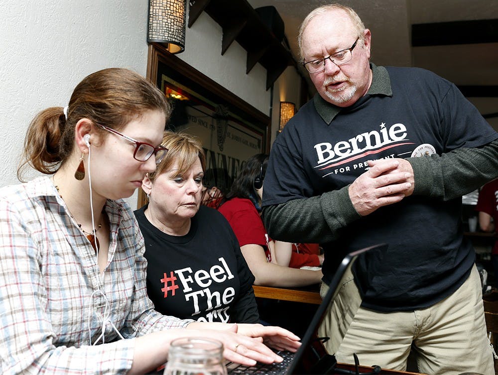 Ruth Simcox, center, and Dave Simcox help Mary Migliozzi to connect on the line to call for phone banking Sunday at the Nick's English Hut. Local volunteers for Bernie Sanders along with members of "IU Students for Bernie Sanders" organized a phone banking to generate datas from calling. 