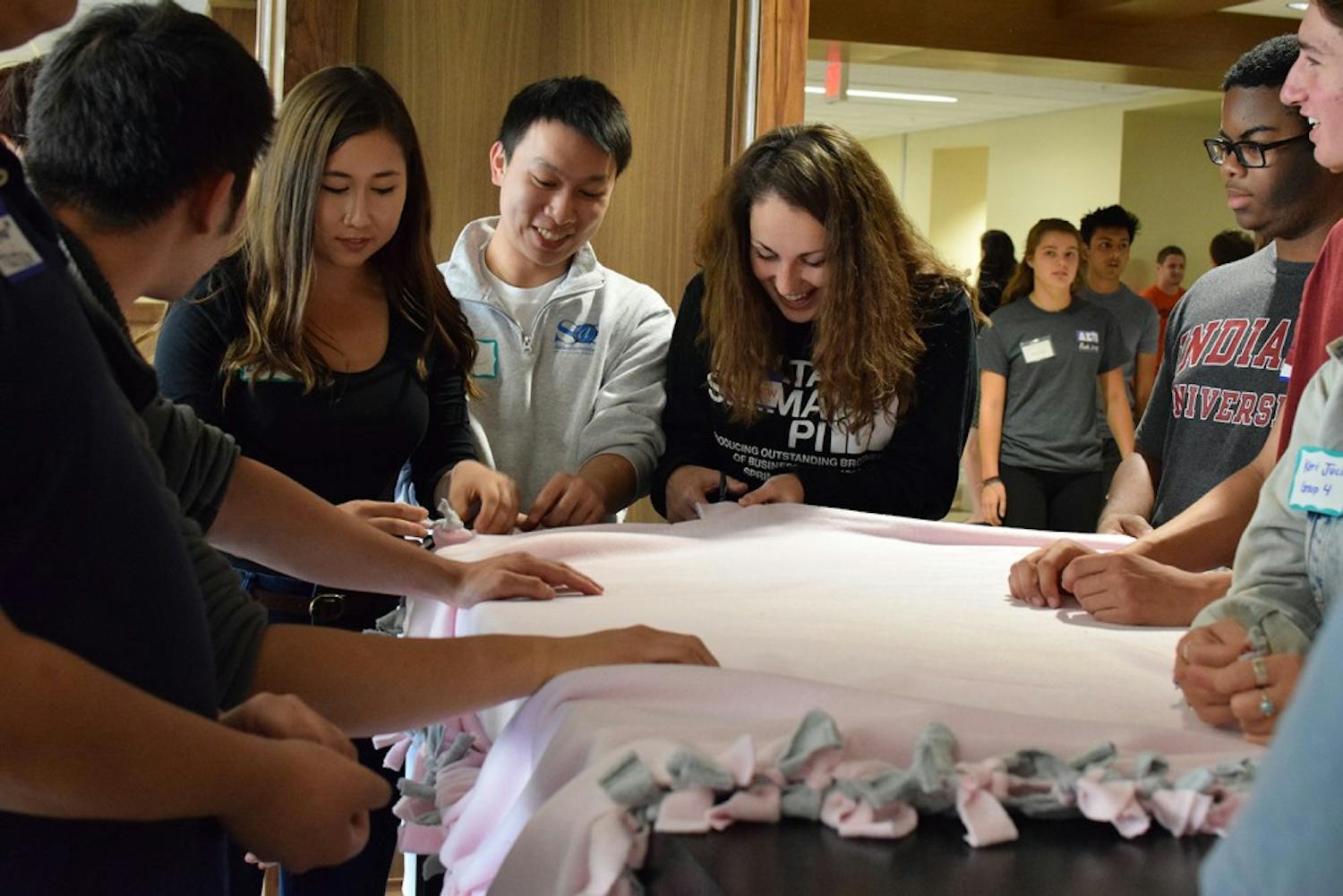 Rushing junior Matt Cheong and senior member Jamie Ventin cut the edges of a fleece blanket at the Delta Sigma Pi Community Service Event in Hodge Hall September 14, 2015. The event was part of the fraternity's Fall 2015 Rush schedule and the IFC is preparing to begin their new rushing process in September.