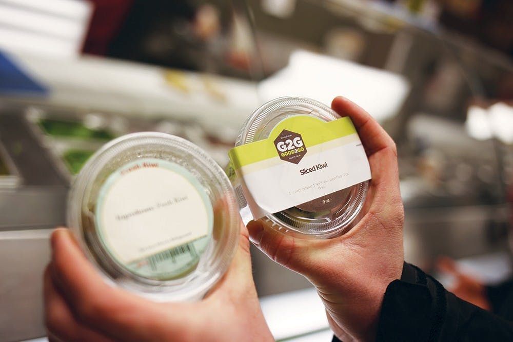 Freshman Wes Wagner compares side-by-side the old RPS food packaging with the new G2G packaging Wednesday evening in the Union Street Market. He said that he chose the cantalopue packaged with the G2G label at Wright Food Court Wednesday morning because the new branding made it look fresher.  