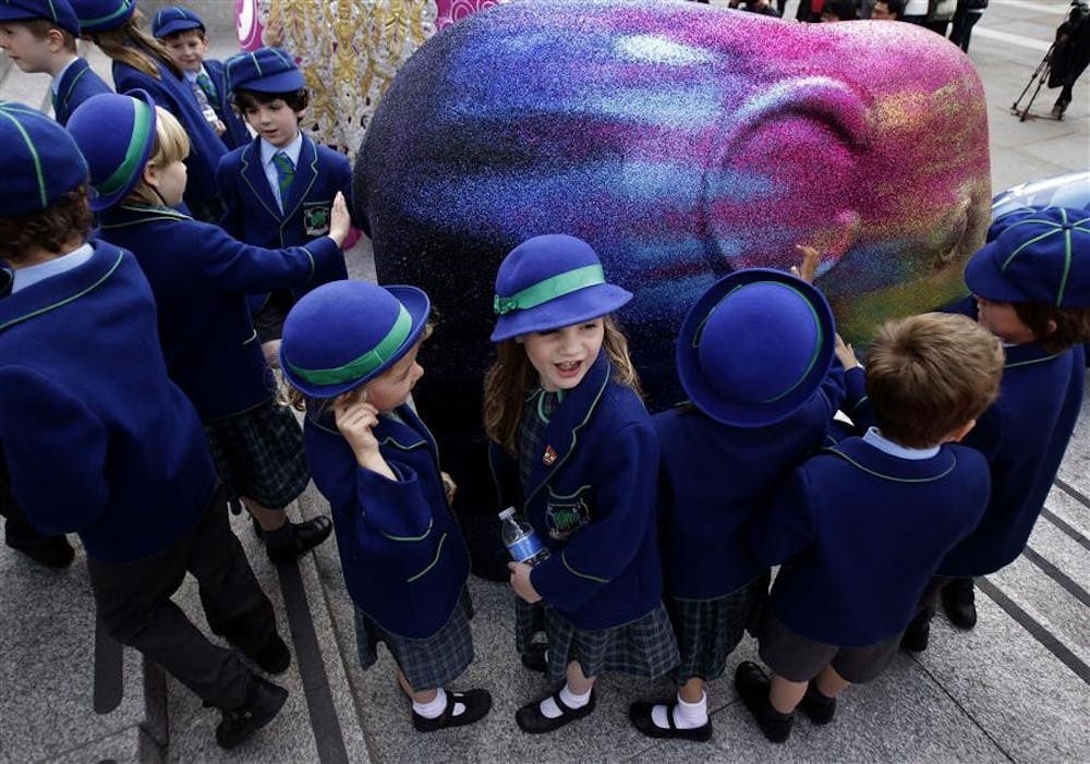 School children look and touch an elephant artwork in Trafalgar Square in London, Tuesday, May 4, 2010. The London Elephant Parade 2010 will see the capital taken over by 260 life-size baby elephants, all hand-painted by an assortment of established and emerging talent from the art and design world.(AP Photo/Matt Dunham)