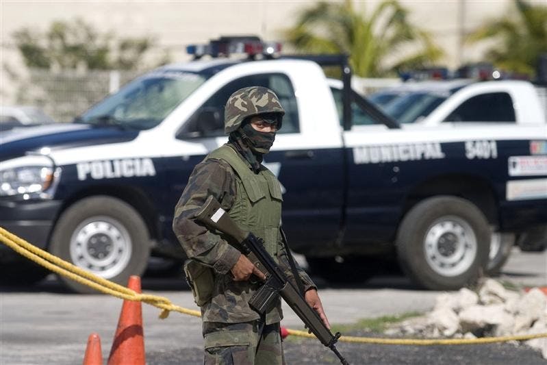 A soldier guards police vehicles Monday outside a police station in Cancun, Mexico. The Mexican military has been reviewing the gun licenses of Cancun's police officers saying it was a routing check, although officers say it was part of the investigation into the killing of retired Mexican brigadier general and two other men, whose bodies were found last Feb. 3.