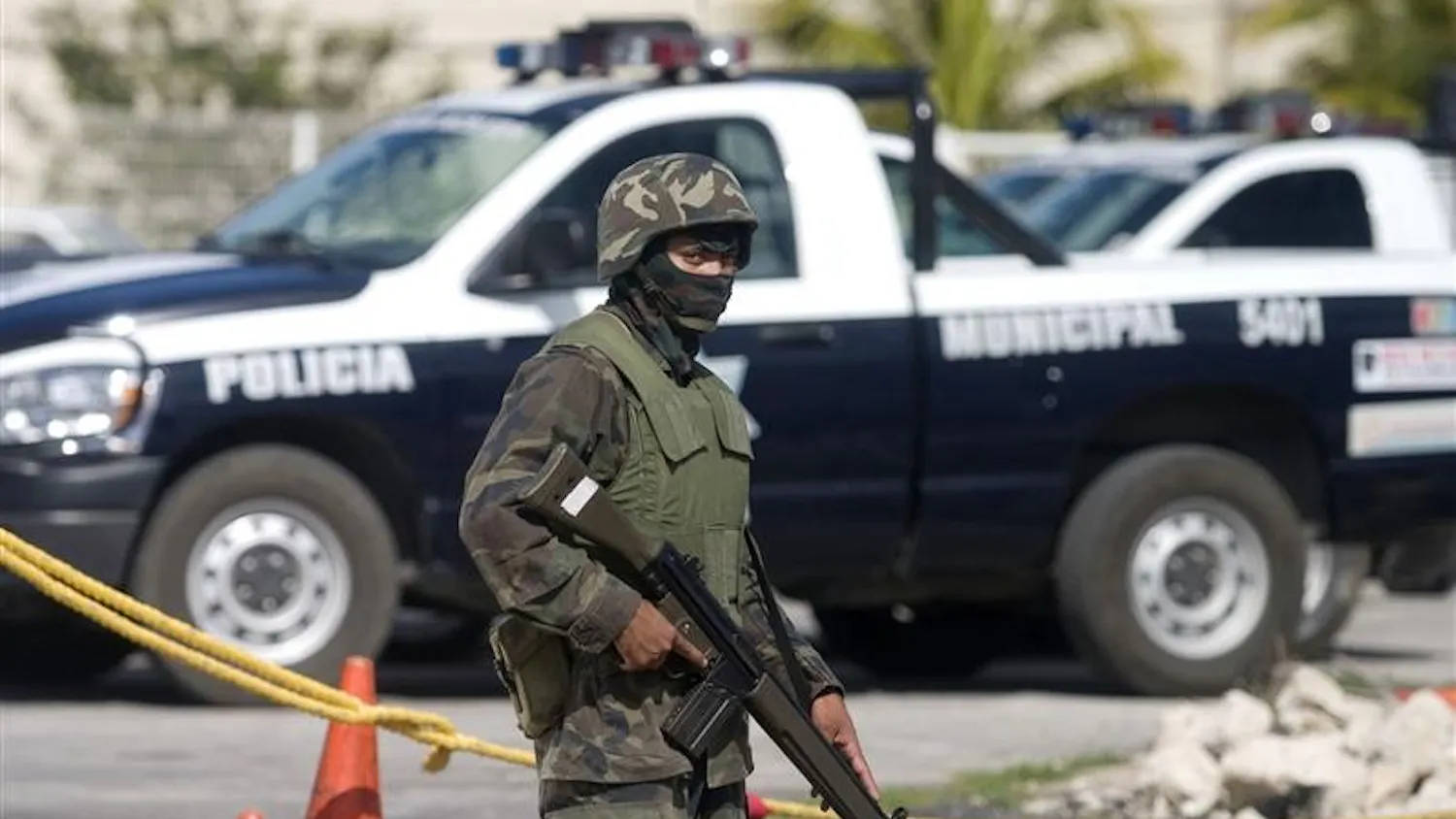 A soldier guards police vehicles Monday outside a police station in Cancun, Mexico. The Mexican military has been reviewing the gun licenses of Cancun's police officers saying it was a routing check, although officers say it was part of the investigation into the killing of retired Mexican brigadier general and two other men, whose bodies were found last Feb. 3.