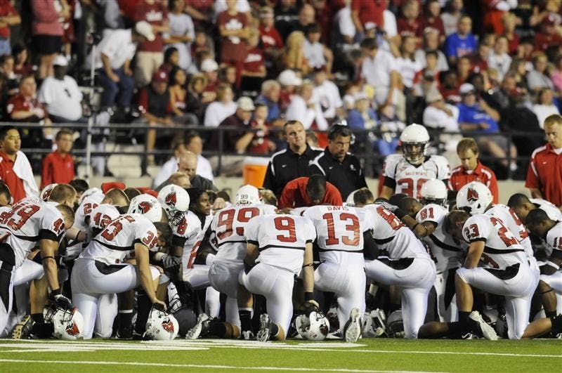 Ball State players gather to pray while the medical staff helps teammate Dante Love on Saturday night in Memorial Stadium. Love was motionless on the ground after getting hit by an IU defender and was taken off the field on a stretcher.