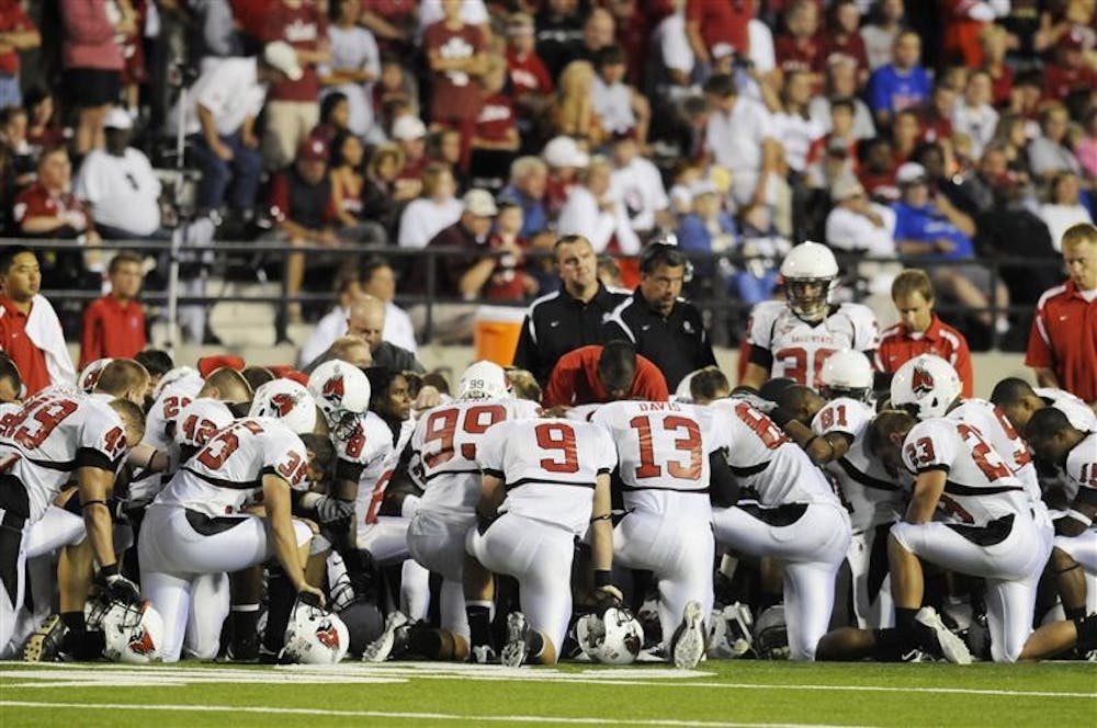 Ball State players gather to pray while the medical staff helps teammate Dante Love on Saturday night in Memorial Stadium. Love was motionless on the ground after getting hit by an IU defender and was taken off the field on a stretcher.