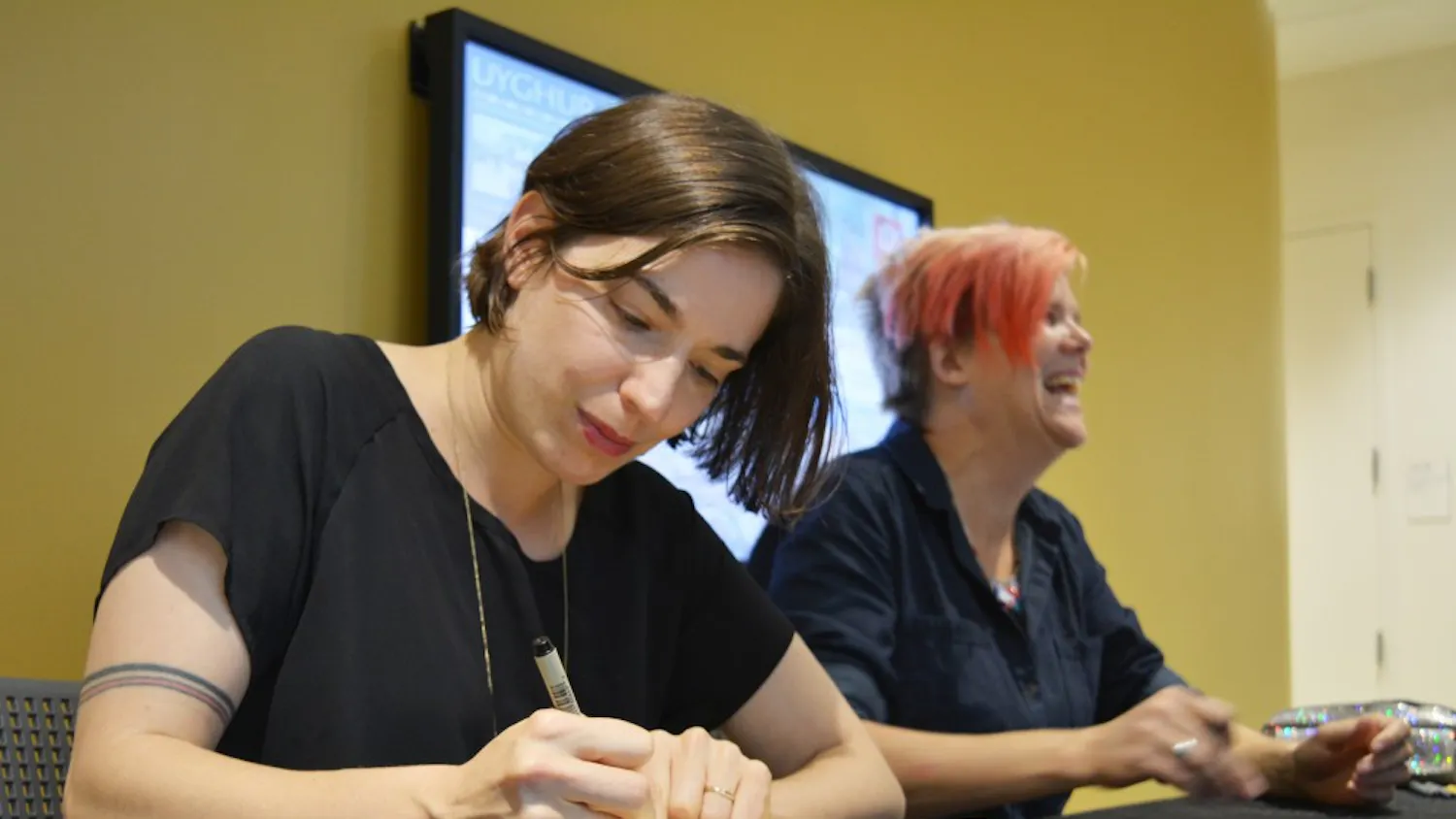 Journalistic cartoonist Sarah Glidden signs her book, "Rolling Blackouts" after the Refugees, Art and Journalism talk Monday night. She said she used universal symbols she saw abroad, such as a blue plastic chair, to show how Western culture connects to the Middle East and refugee crisis.