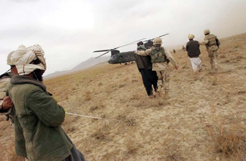 ZABOL PROVINCE, AFGHANISTAN - APRIL 2: Afghan detainees are walked to a Chinook helicopter for transport by Special Operation Forces after a joint village raid between U.S. Special Forces and the Afghan National Army April 2, 2004 in southeast Afghanistan. U.S. Special Forces and the Afghan National Army, trained by special forces and U.S. Marines, are together stepping up the hunt for Taliban and al Qaeda forces. The deployment of the ANA to the southeast marks the first time the army has been seen by locals in this region. (Photo by Darren McCollester/Getty Images)