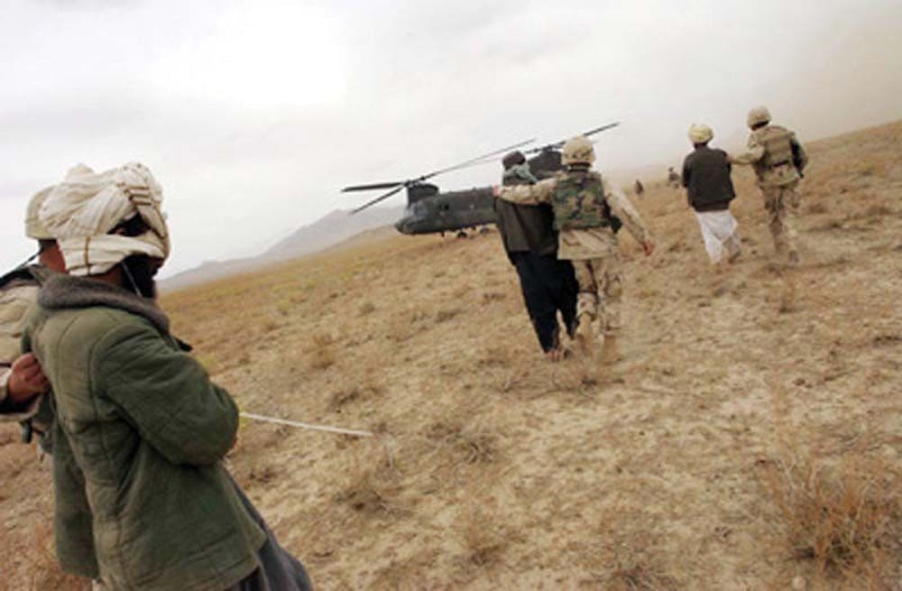 ZABOL PROVINCE, AFGHANISTAN - APRIL 2: Afghan detainees are walked to a Chinook helicopter for transport by Special Operation Forces after a joint village raid between U.S. Special Forces and the Afghan National Army April 2, 2004 in southeast Afghanistan. U.S. Special Forces and the Afghan National Army, trained by special forces and U.S. Marines, are together stepping up the hunt for Taliban and al Qaeda forces. The deployment of the ANA to the southeast marks the first time the army has been seen by locals in this region. (Photo by Darren McCollester/Getty Images)