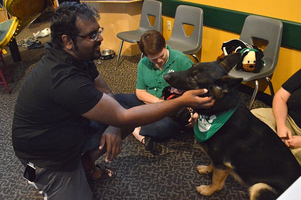 Vamsi Vallurupalli learns about the dogs of the Monroe County Human Society from Lori Shields at the WonderLab on Sunday.