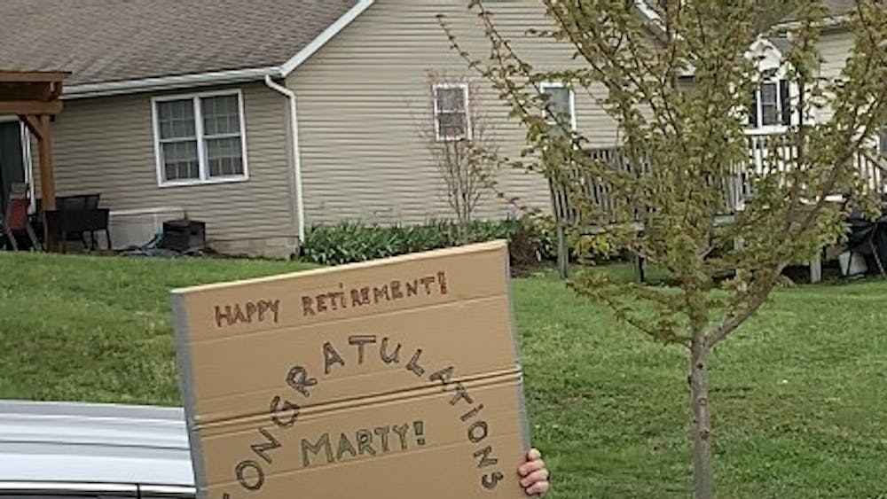 Erik Stolterman Bergqvist, senior executive associate dean of the Luddy School of Informatics, holds a sign out of a car Thursday. Bergqvist participated in surprise parade for retiring professor Marty Siegel.