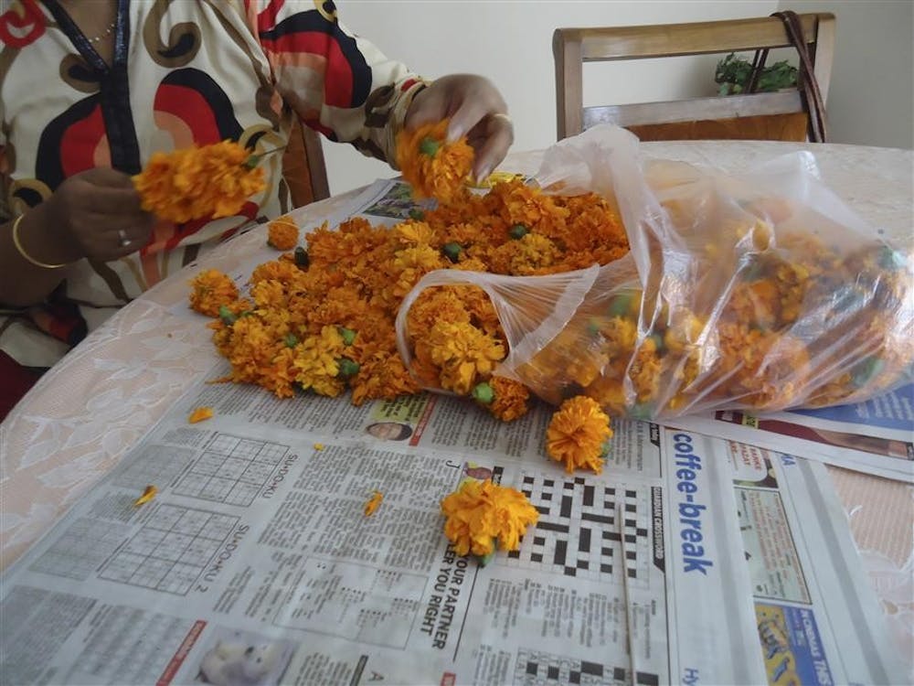 My host mom, affectionately known as Lathaji, strings marigold flowers onto thread to create a garland for our door.