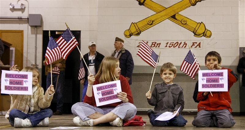 Jayden Boyer, left, Andrea Dahl, James Boyer and Tyler Davis sit and wait for soldiers to arrive on Monday, Dec. 1 at Camp Atterbury near Edinburg, Ind. The children had no relatives serving.  Their father, Andrew Long, who now lives in Bloomington, served in the Australian Air Force 492 Squadron and came to show his support to all the returning soldiers.