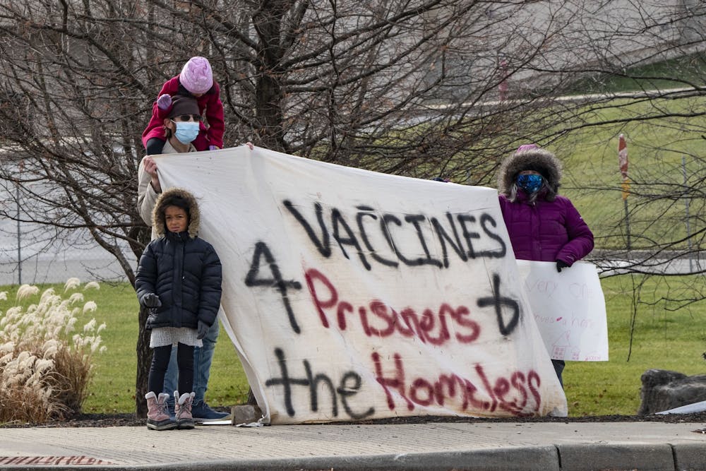 <p>Protesters watch as the vice presidential motorcade arrives Dec. 15, 2020, outside of Catalent in Bloomington. People experiencing homelessness have a high risk of contracting COVID-19.</p>