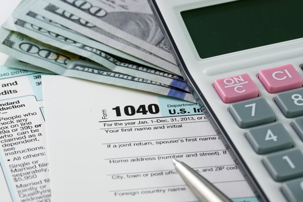 <p>Tax forms and a calculator sit on a table. INFreeFile is one online tax filing system that students could use.</p>