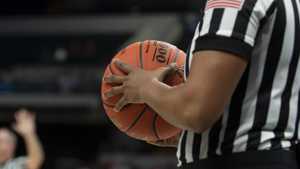 A referee holds a basketball March 6 at Bankers Life Fieldhouse in Indianapolis. IU men&#x27;s basketball team has paused workouts after multiple positive coronavirus cases.