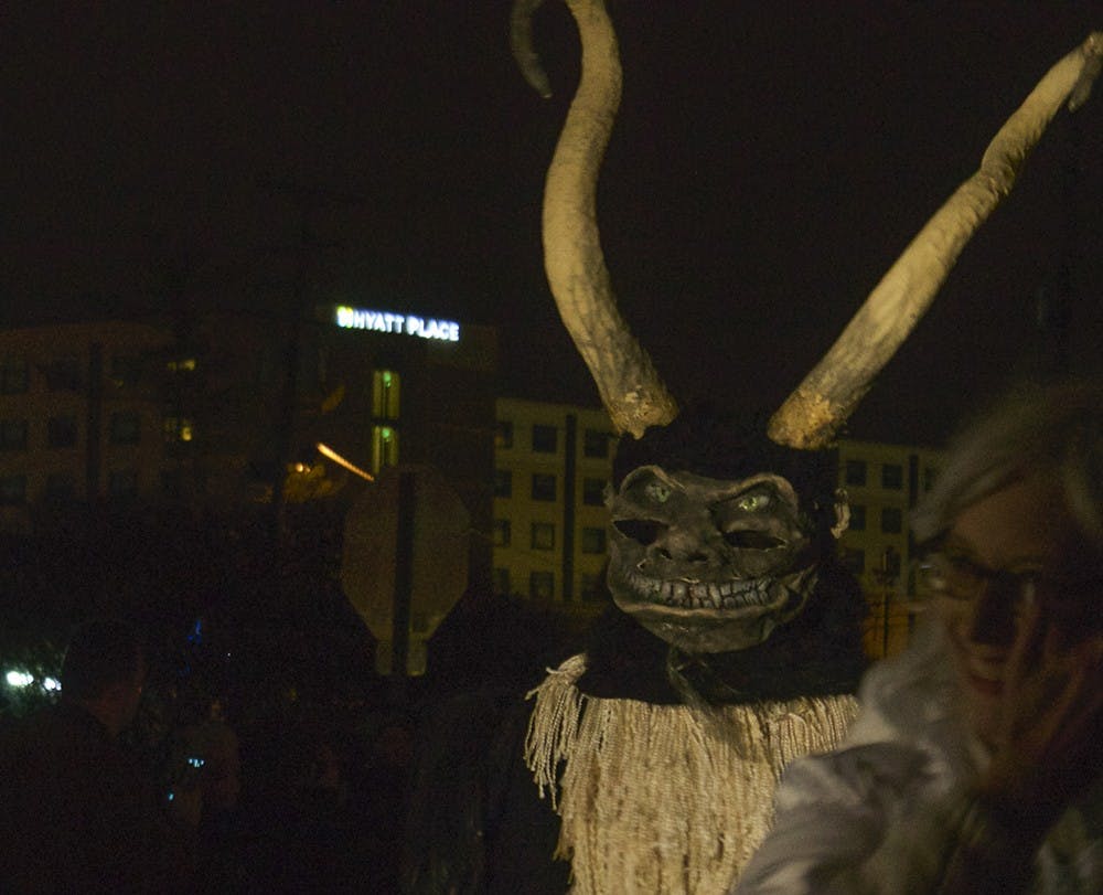 People dress up as demonic followers of Krampus, the "Bad Santa," during the Krampus parade Saturday in downtown Bloomington. The creatures walked down Madison Street and taunted people wearing "Naughty" stickers.