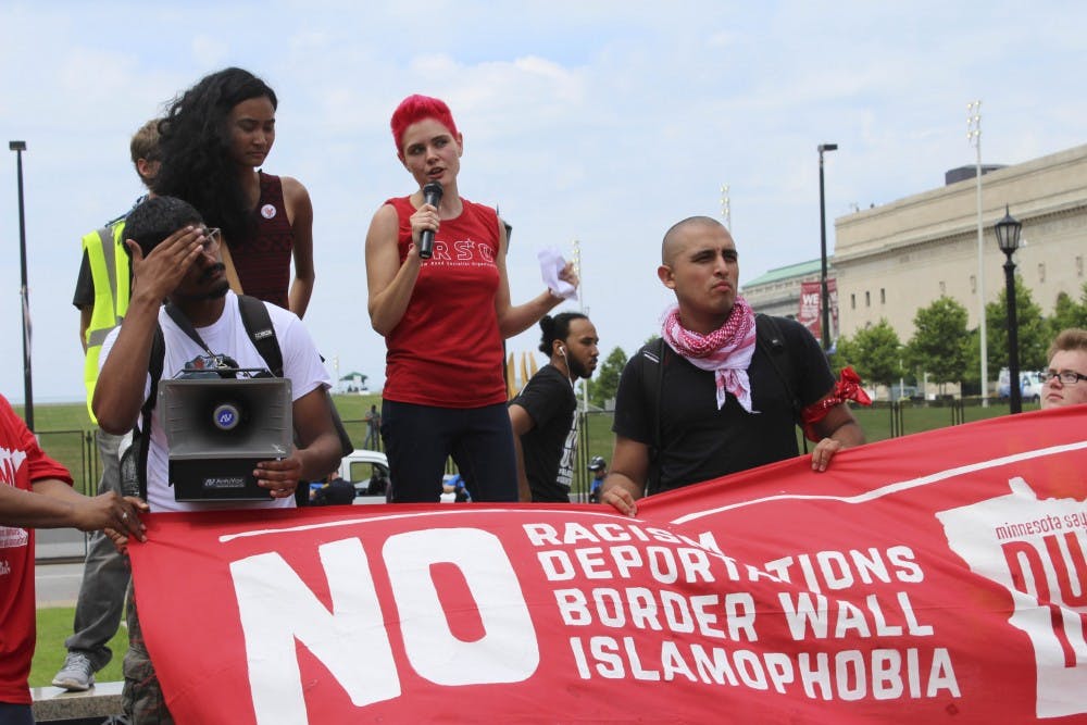 Kait McIntyre, 27, speaks to the crowd at the end of the march at the Veterans Memorial Square. She tells participants they must all work together to end racism and defeat Trum​p. 