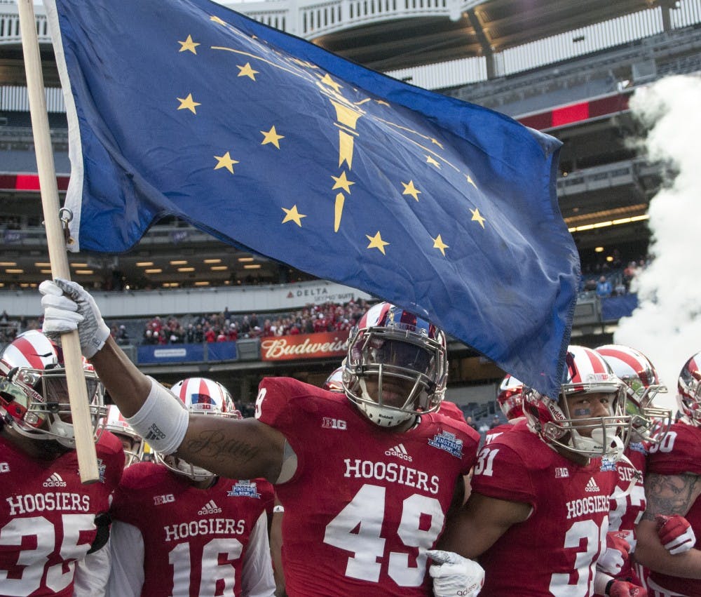 Greg Gooch carries the Indiana flag before running onto the field before the Pinstripe Bowl against Duke on Dec. 26 at Yankee Stadium. The Hoosiers lost, 44-41 in overtime.