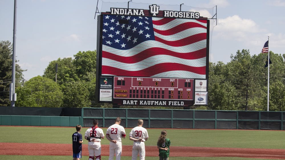 Then-senior catcher Ryan Fineman, then-junior left-handed pitcher Andrew Saalfrank and then-junior infielder Scotty Bradley stand with two children on the pitching mound May 18, 2019, at Bart Kaufman Field. Indiana Athletics announced Monday that fans over the age of 21 will be able to purchase beer at Indiana baseball and softball home games.