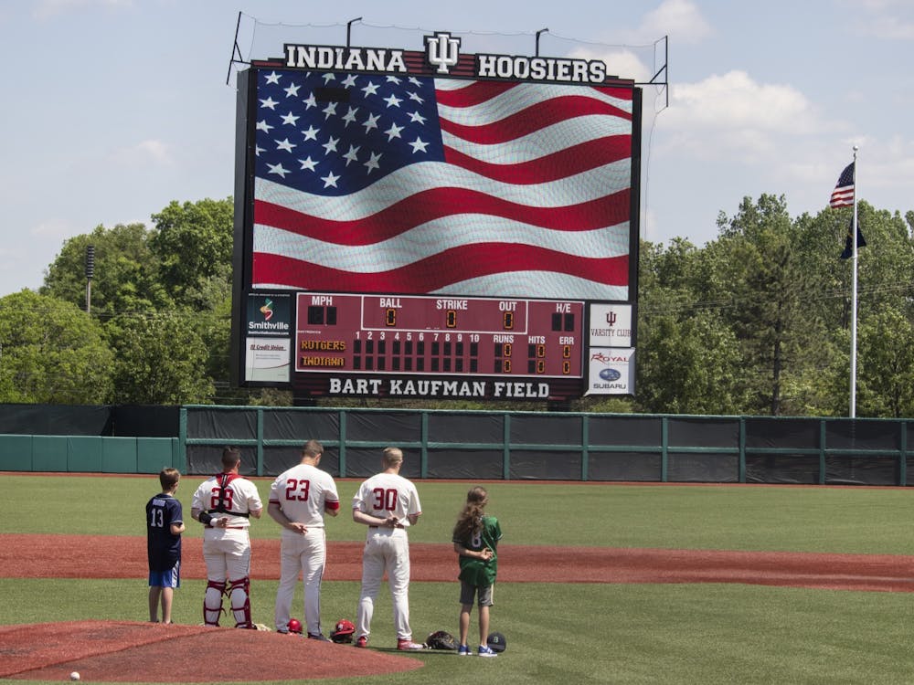 Then-senior catcher Ryan Fineman, then-junior left-handed pitcher Andrew Saalfrank and then-junior infielder Scotty Bradley stand with two children on the pitching mound May 18, 2019, at Bart Kaufman Field. Indiana Athletics announced Monday that fans over the age of 21 will be able to purchase beer at Indiana baseball and softball home games.