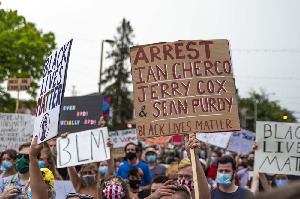 7月6日，一名抗议者举着一个牌子，上面写着据信在7月4日袭击沃xx布克的三名男子的名字。抗议者先是聚集在门罗县法院，然后在市中心游行，最终回到法院的草坪上。