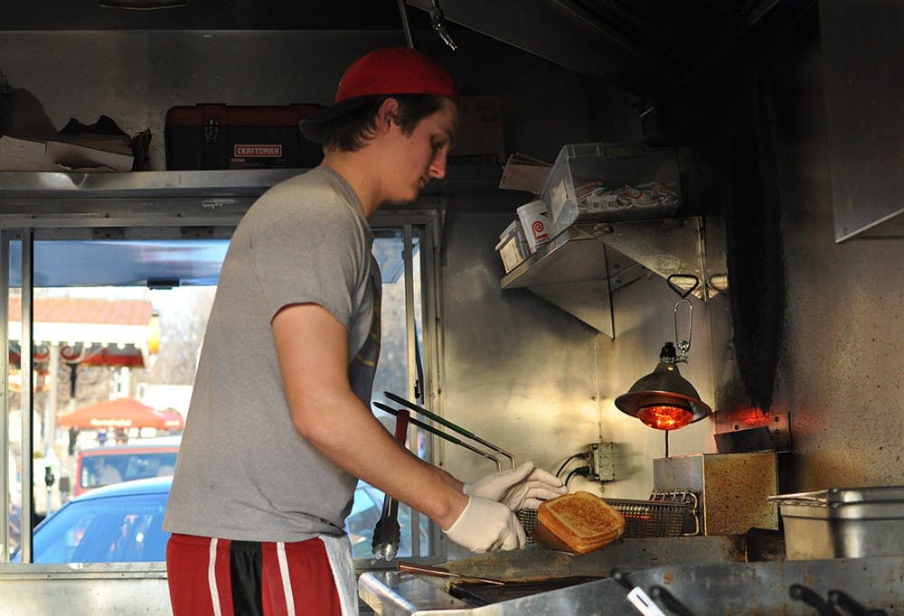 Levi Long prepares sandwiches in the Big Cheeze food truck, parked on Kirkwood Ave on Wednesday. The proposed new rules would ban the food truck from operating in this and many other locations.