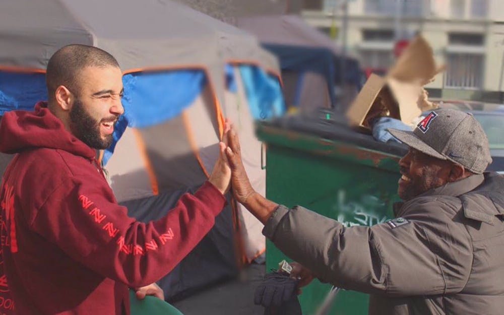 Josh Yazdian (left) high fives a homeless man in Los Angeles. Yazdian has donated thousands of clothing items to the homeless through his company, Yaz Apparel.