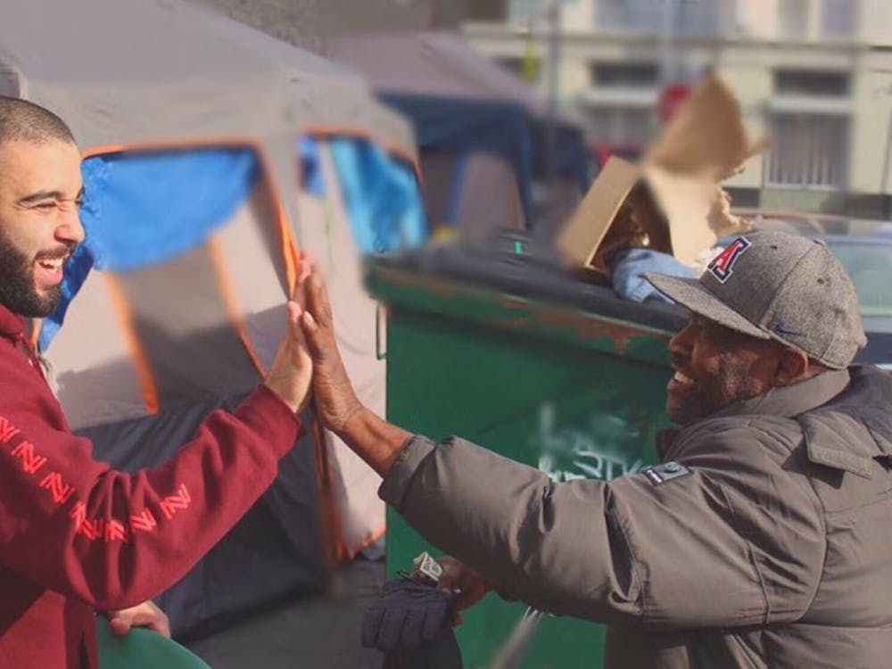 Josh Yazdian (left) high fives a homeless man in Los Angeles. Yazdian has donated thousands of clothing items to the homeless through his company, Yaz Apparel.