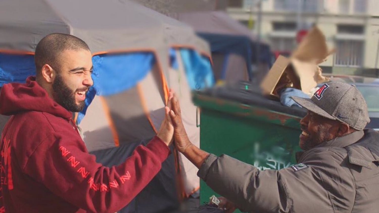 Josh Yazdian (left) high fives a homeless man in Los Angeles. Yazdian has donated thousands of clothing items to the homeless through his company, Yaz Apparel.