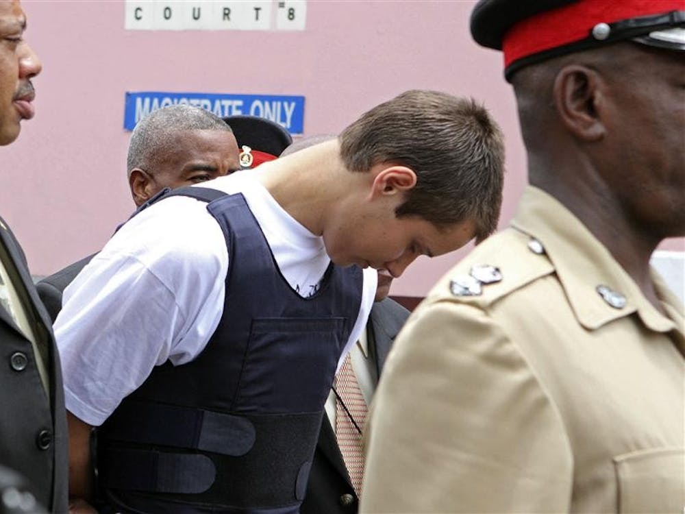 Colton Harris-Moore, the teenage fugitive police have dubbed the "Barefoot Bandit," is escorted handcuffed by Bahamian authorities to the court building in Nassau, Tuesday July 13, 2010.  Harris-Moore, who was captured following a high-speed boat chase on Sunday in Eleuthera island, pleaded guilty to a minor offense in the Bahamas and is expected to be deported soon to the U.S. to face prosecution. (AP Photo/Tim Aylen)